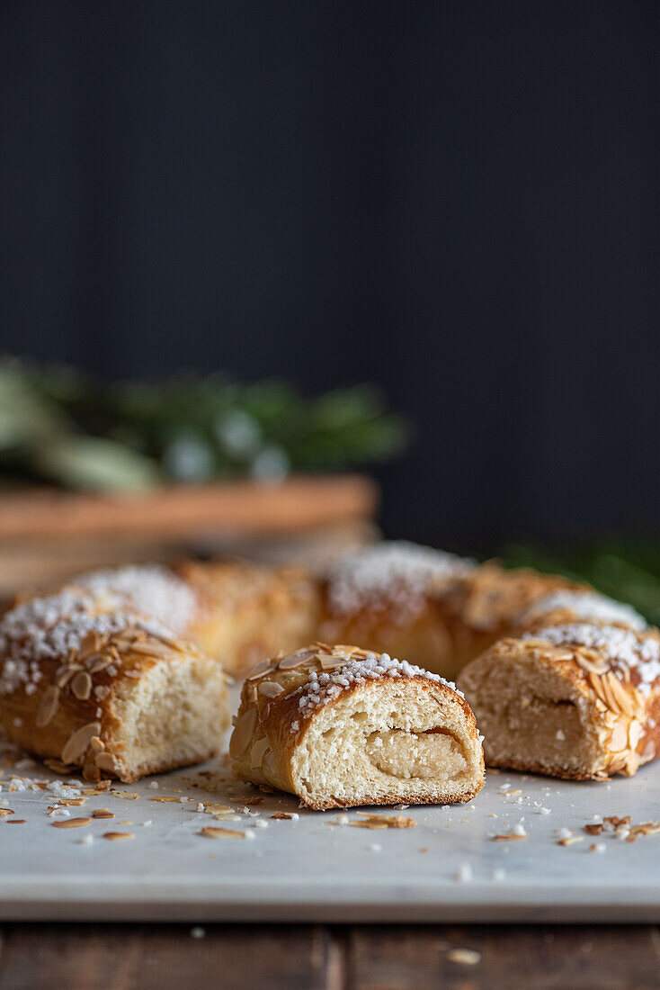 Köstliche Dreikönigskuchenstücke mit Kokosnussflocken und Mandelblättern während des Dreikönigsfestes auf dunklem Hintergrund