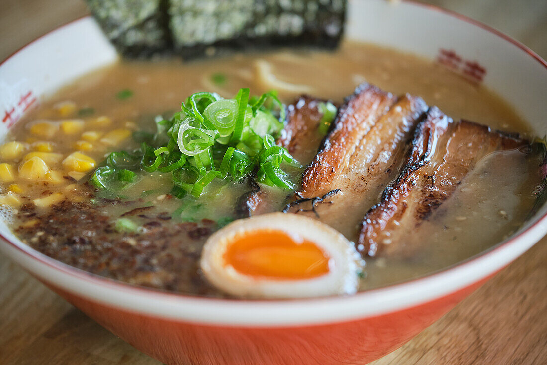 Stock photo of yummy ramen soup with boiled egg and meat in japanese restaurant ready to be served.