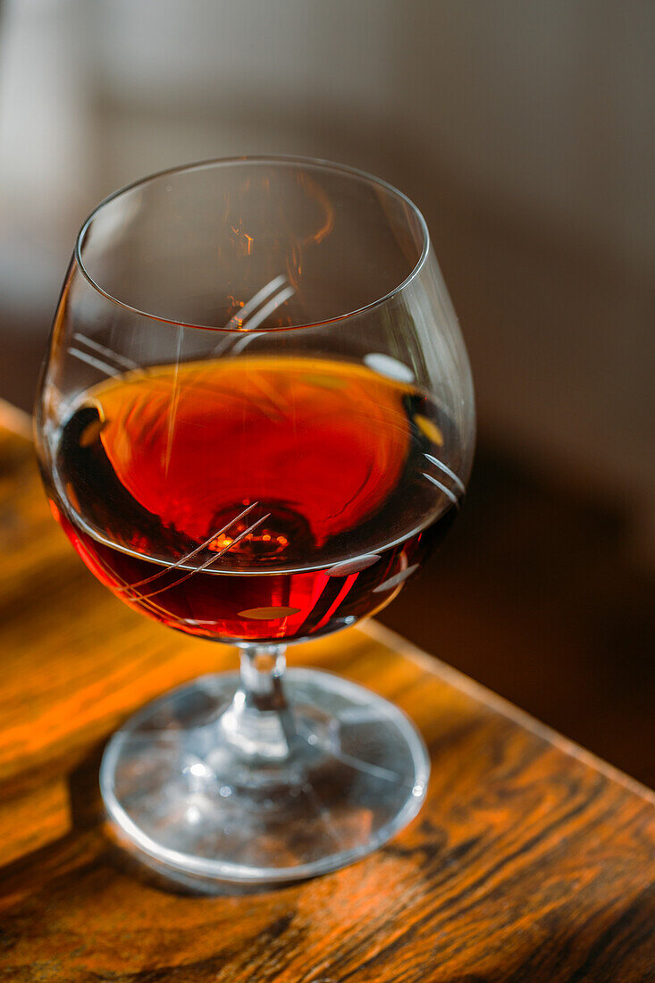 Old fashioned cognac glass on wooden table with natural light