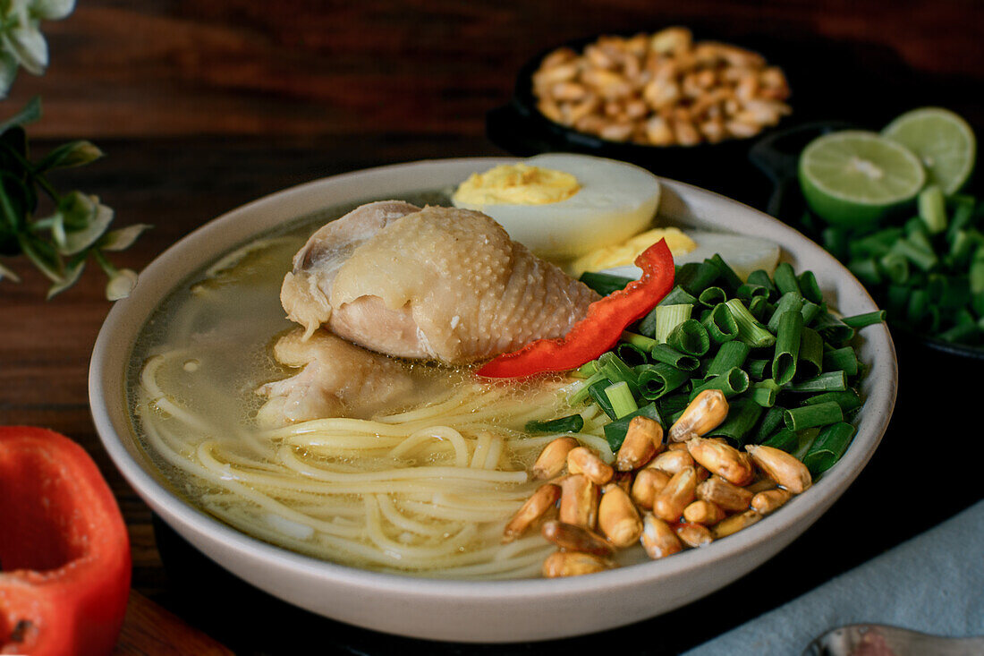 From above of appetizing fresh chicken broth with assorted ingredients served in bowl on table in kitchen