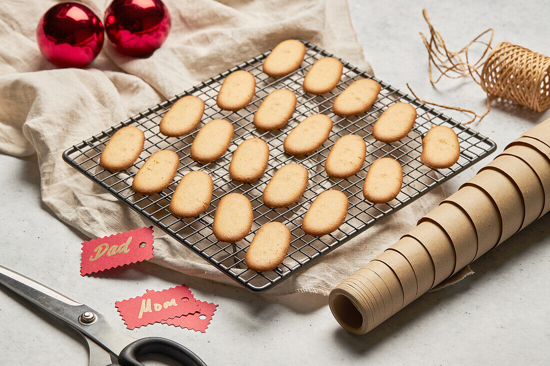 Leckere Weihnachtsplätzchen von oben auf einem Metall-Backnetz auf einem Tisch mit verschiedenen Verpackungsmaterialien