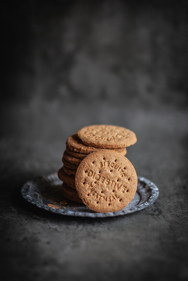 From above of pile of tasty sweet crumbly round digestive biscuits placed on silver tray on gray background