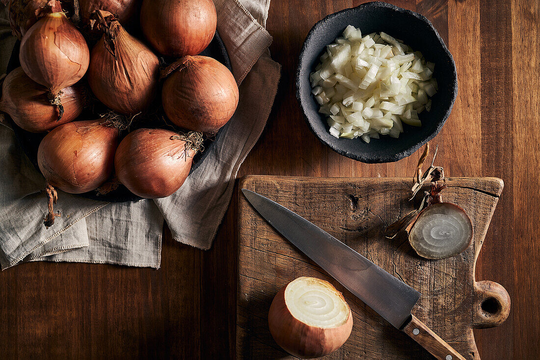 Top view of rustic bowl with pieces of cut onion placed near knife on lumber table in kitchen