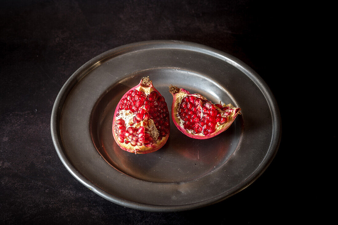 From above of sweet ripe pomegranate pieces served on plate on black table