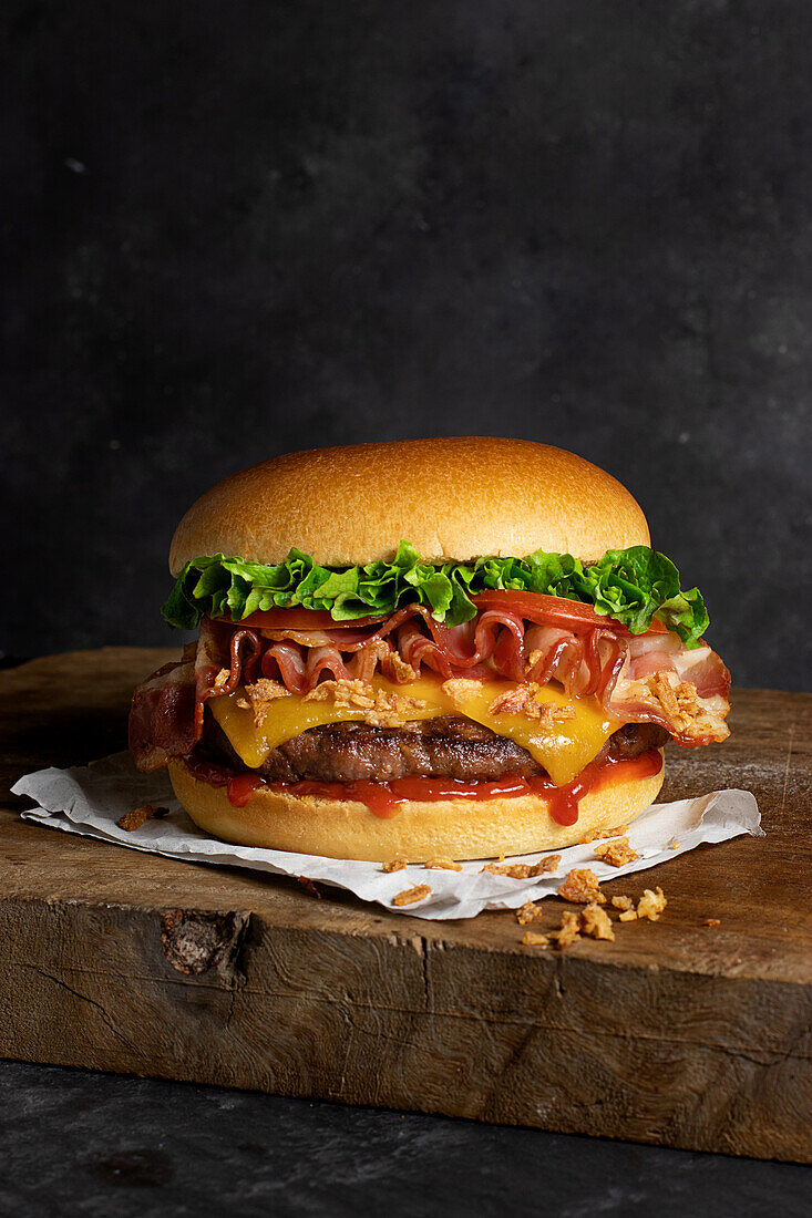 Detailaufnahme eines leckeren Burgers mit Käse und Speck auf dem Holztisch