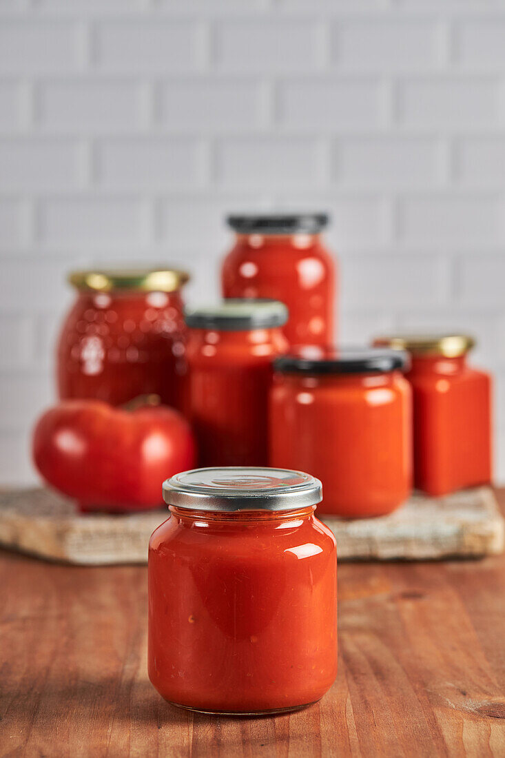 Sealed glass jar with handmade tomato sauce placed on table in kitchen at home