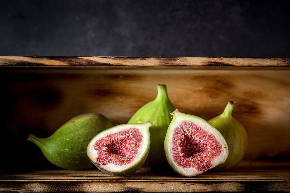 Ripe halved and whole figs placed on wooden rustic table