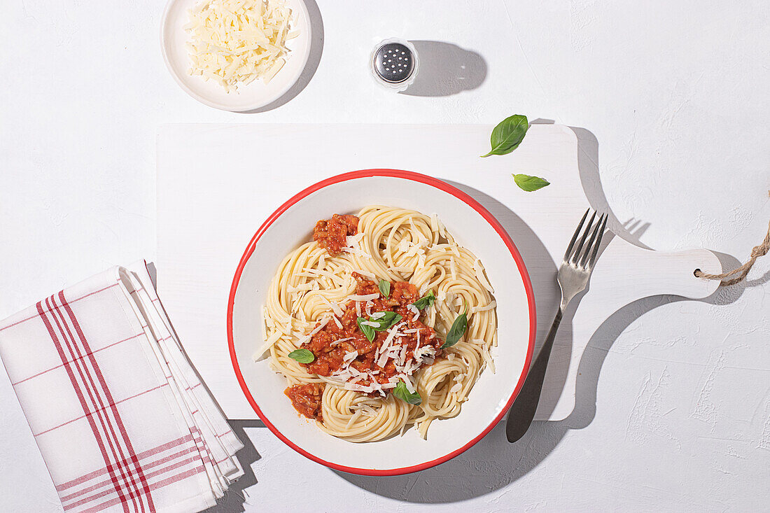 Top view of plate with spaghetti Bolognese pasta with tomatoes sauce in white table background