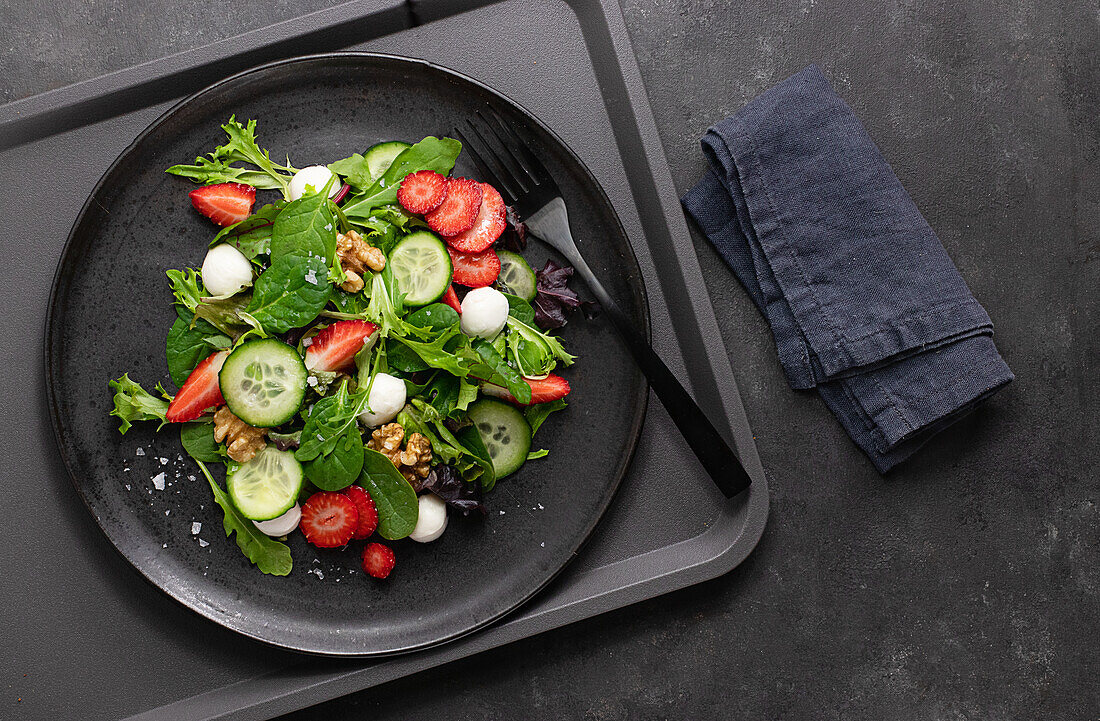 Self-service restaurant with a plate with a summery strawberry and cucumber salad on a tray