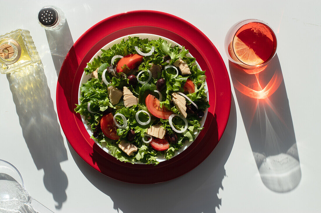 Von oben Thunfischsalat mit Zwiebeln und Tomaten, serviert auf roten Tellern auf weißem Hintergrund