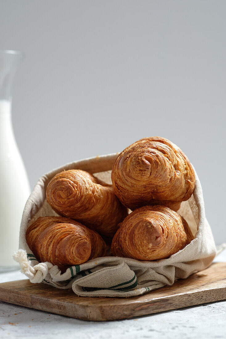 Delicious croissants and bottle of milk placed on table for breakfast in kitchen