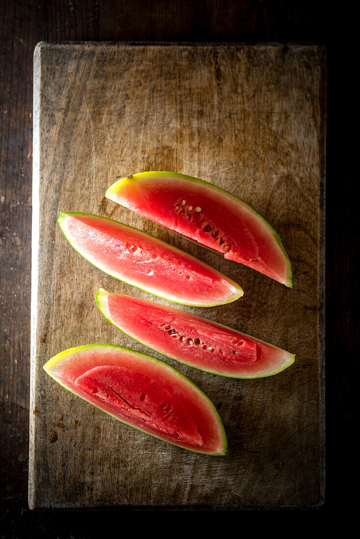 Hoher Winkel von Scheiben reifer süßer Wassermelone auf Holztisch vor dunklem Hintergrund