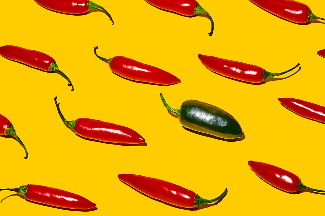 From above of fresh ripe chili peppers with hot green vegetable of different kind on yellow background