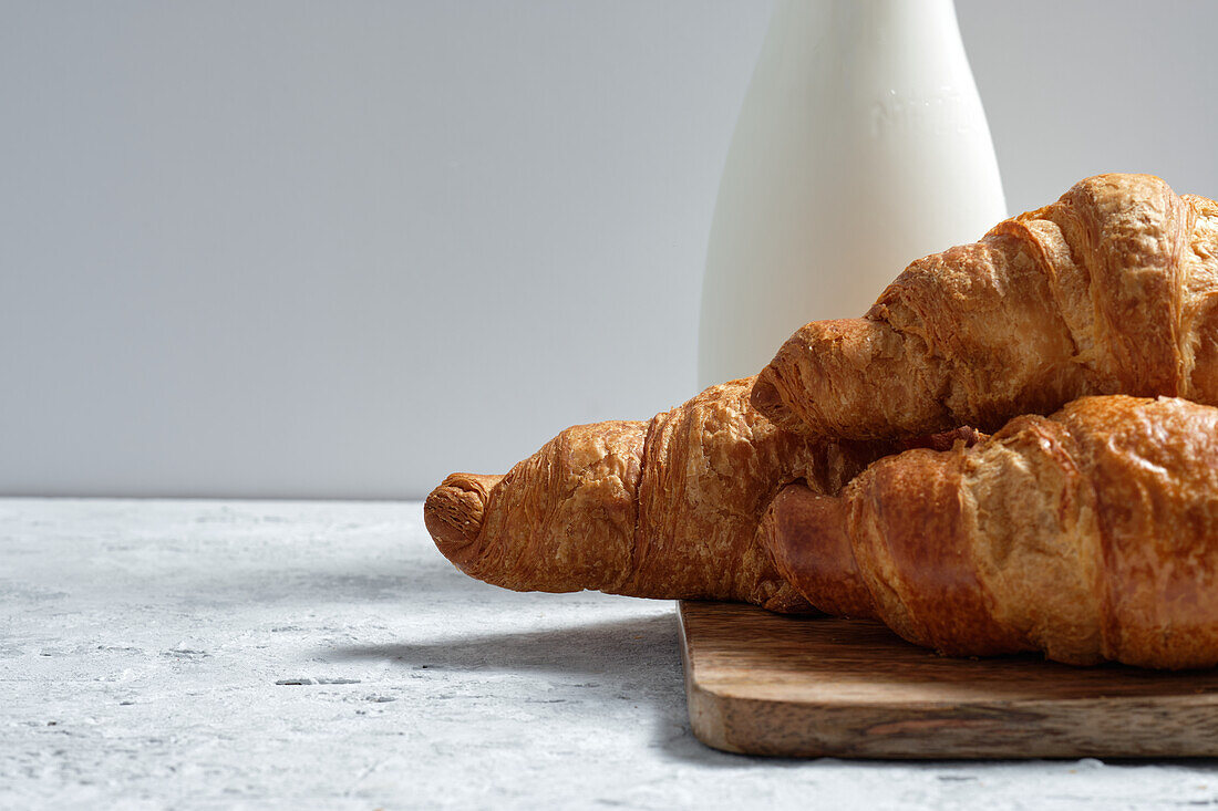 Delicious croissants and bottle of milk placed on table for breakfast in kitchen