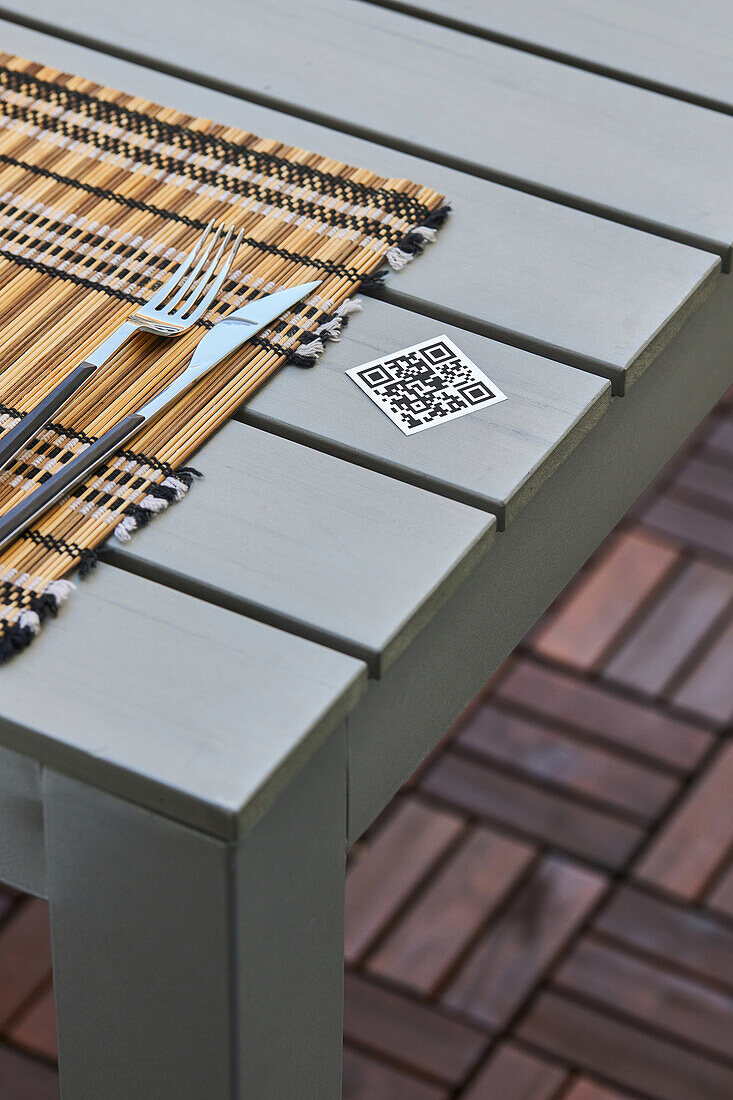 High angle of QR code of menu of Asian restaurant placed on table with napkin and knife and fork