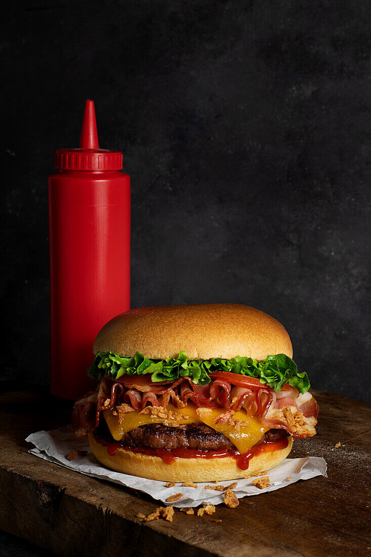 Detail of a delicious burger with cheese and bacon on the wooden table