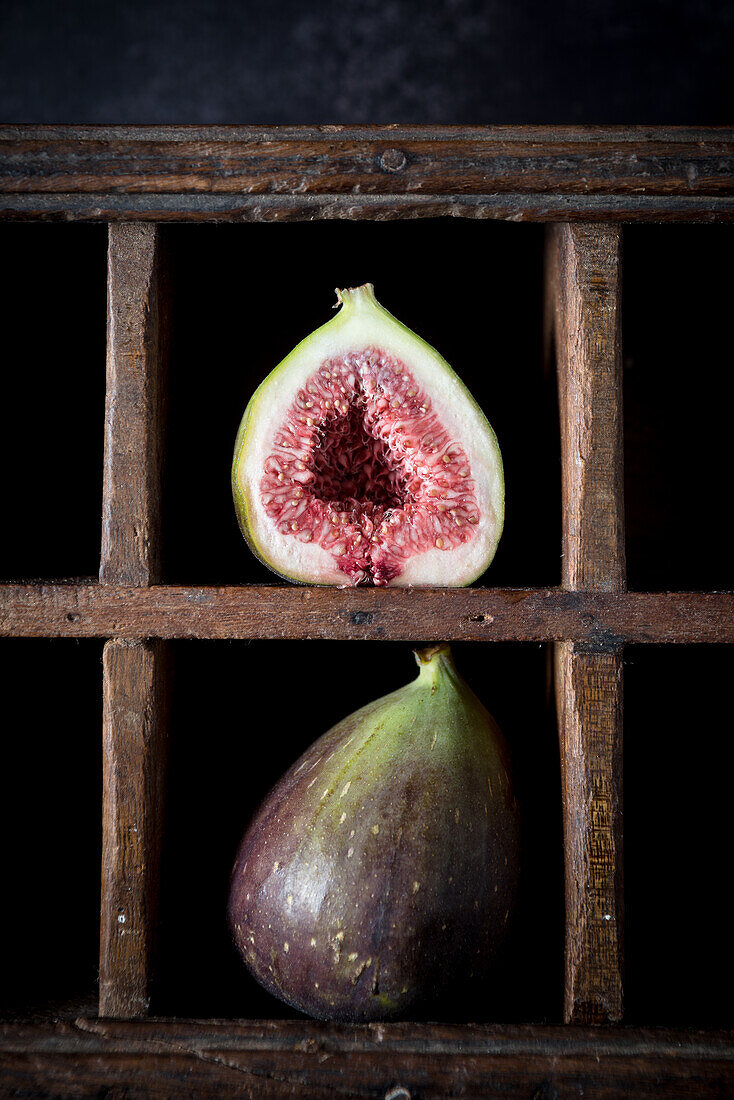 Ripe halved and whole figs placed on shabby wooden shelf on rustic kitchen