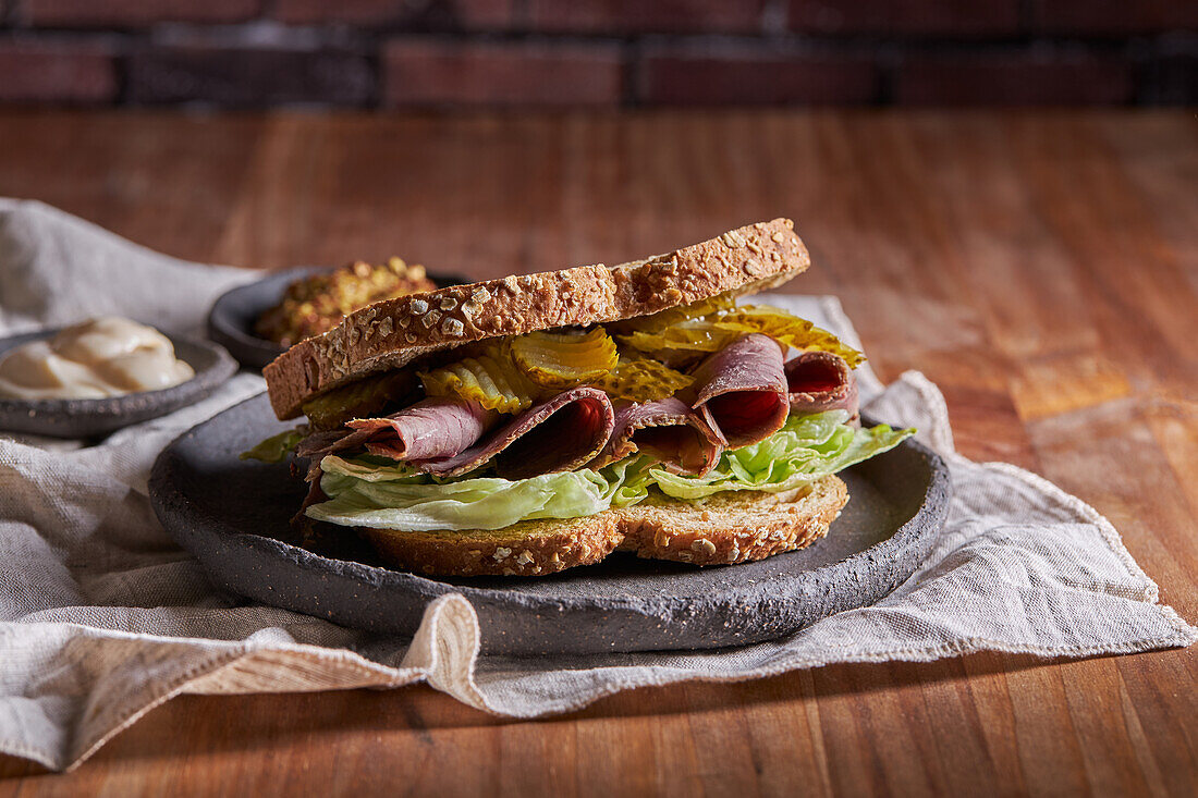 Closeup of a delicious pastrami, lettuce, ham and pickle sandwich