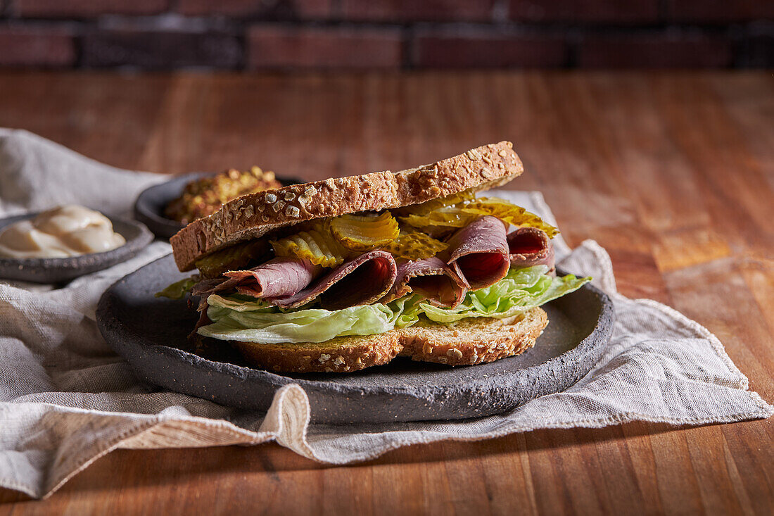 Nahaufnahme eines leckeren Sandwiches mit Pastrami, Salat, Schinken und Gurken