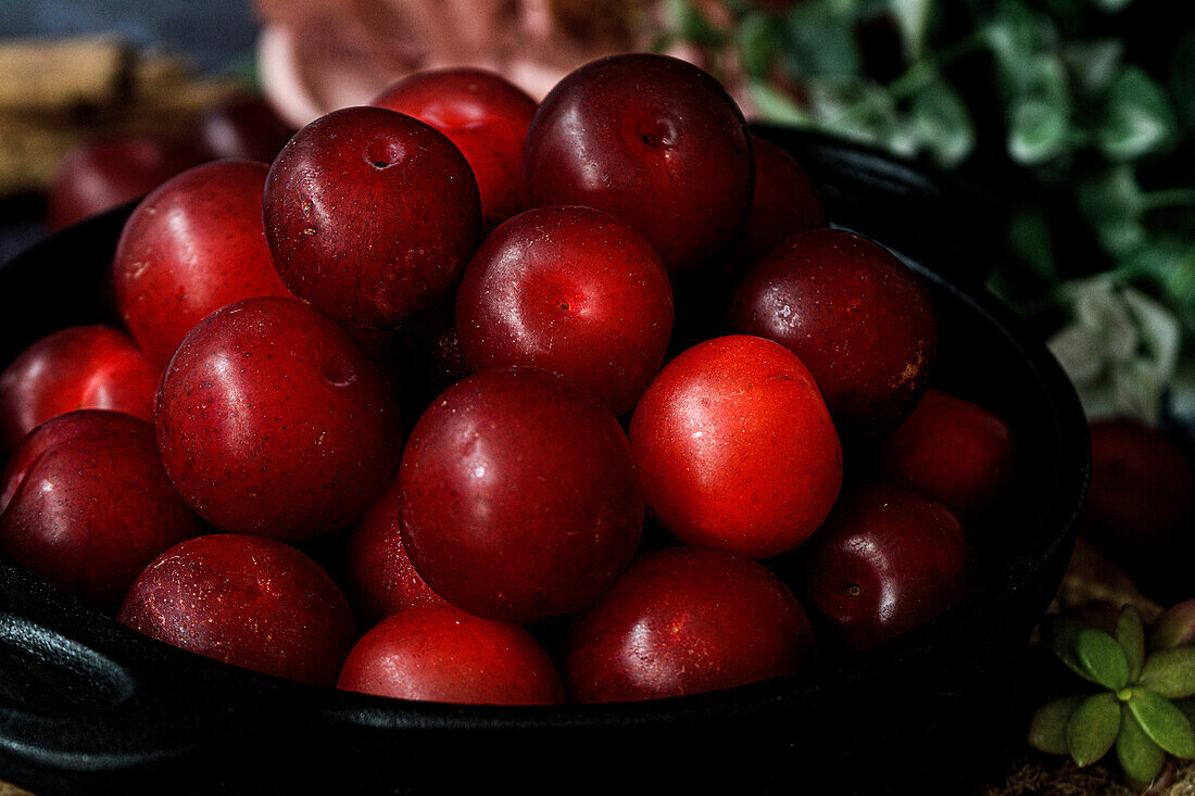 Bowl with fresh sweet plums served on black table