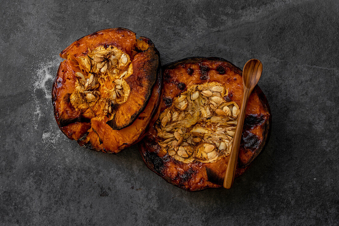 From above of tasty appetizing healthy baked pumpkin halves with seeds on gray table