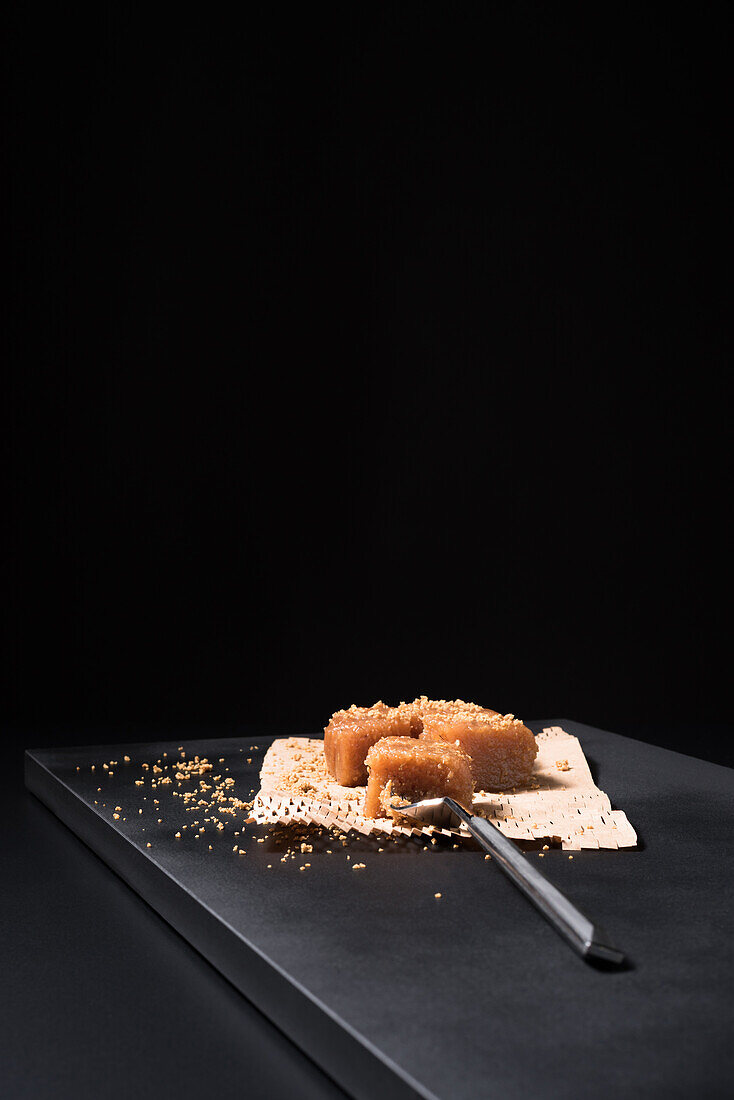 Gourmet quince jelly paste in ceramic plate sprinkled with sesame seeds on black background