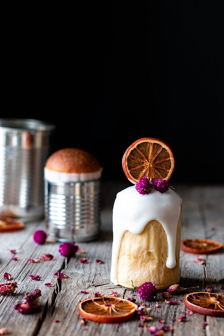 Several delicious homemade kulichs poured with sweet glaze and decorated with pieces of dry orange and flowers on wooden table