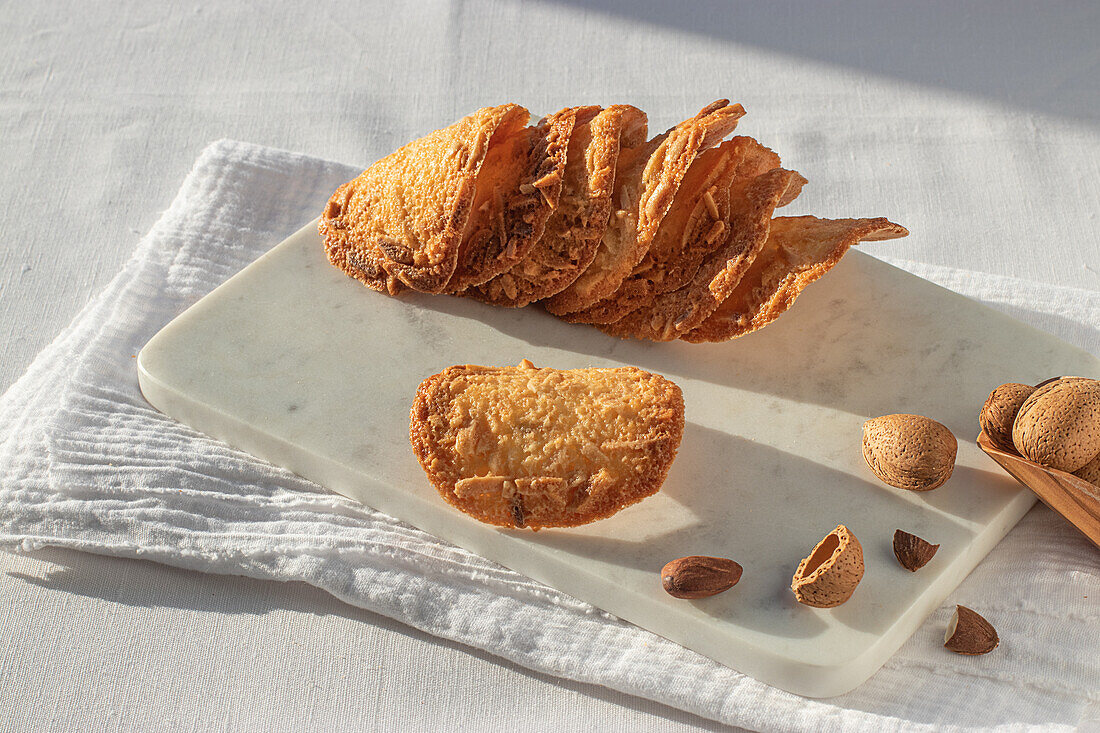 Top view of delicious Almond Tiles cookies placed on plate on tablecloth