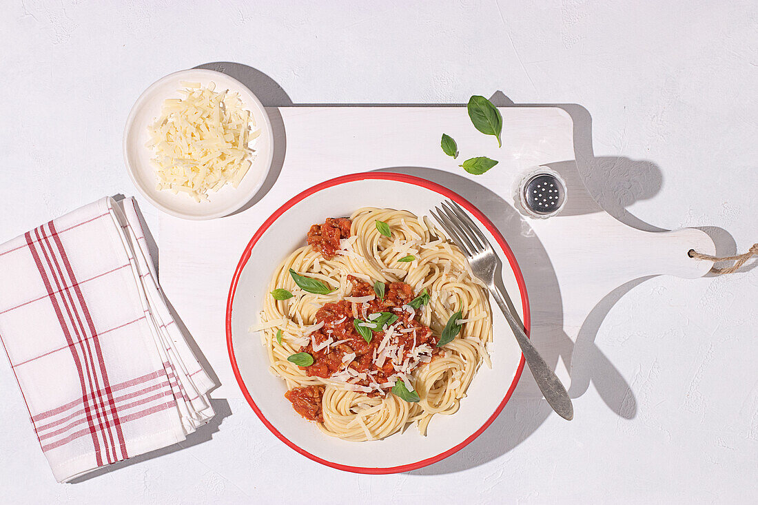 Top view of plate with spaghetti Bolognese pasta with tomatoes sauce in white table background