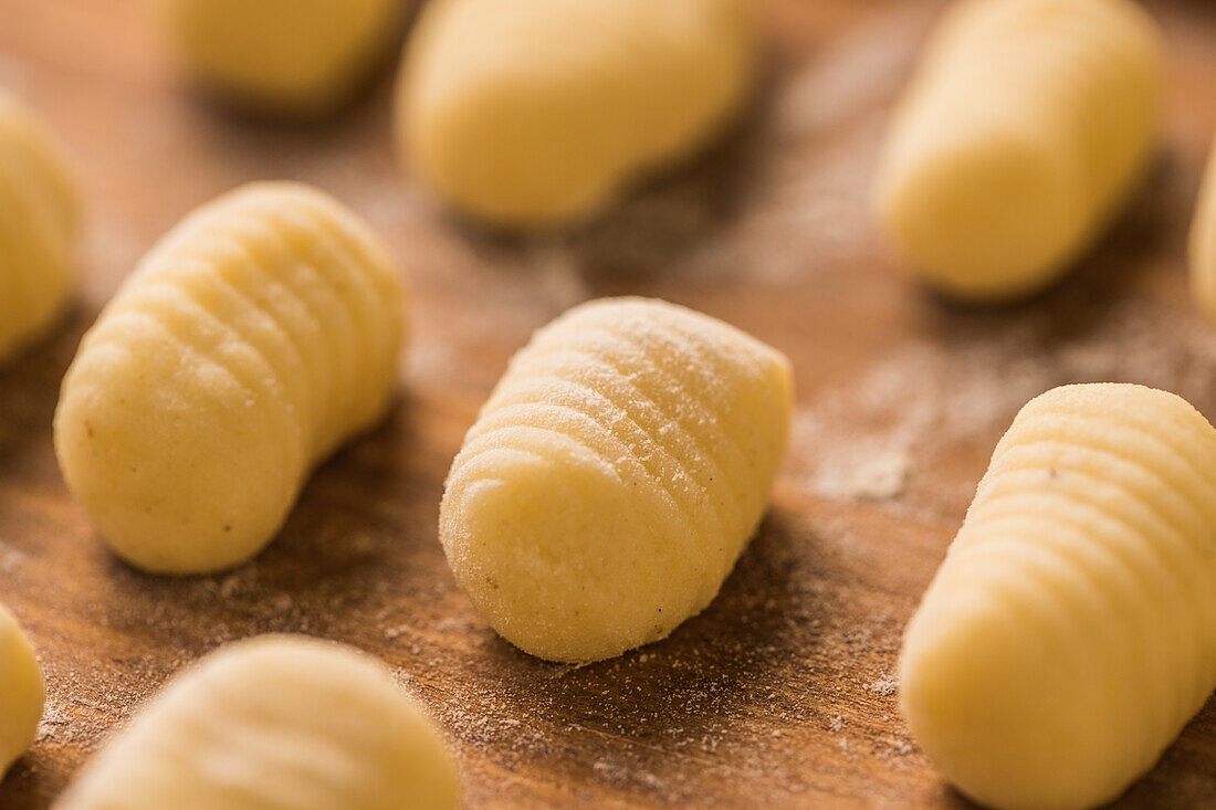 From above top view of uncooked gnocchi placed in organized rows on lumber table during lunch preparation at home