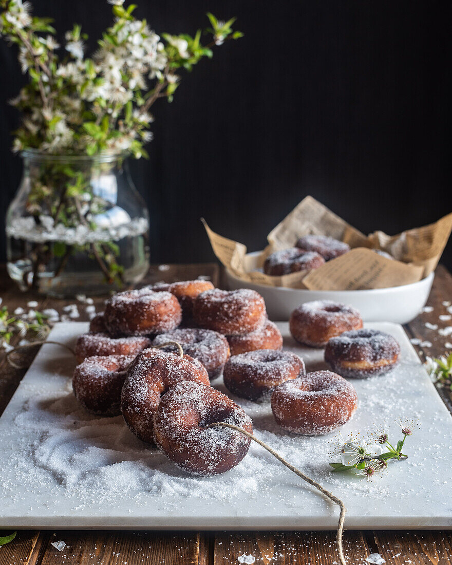 Appetitanregende geliehene süße Donuts auf Faden auf dem Tisch mit gestreutem Puderzucker