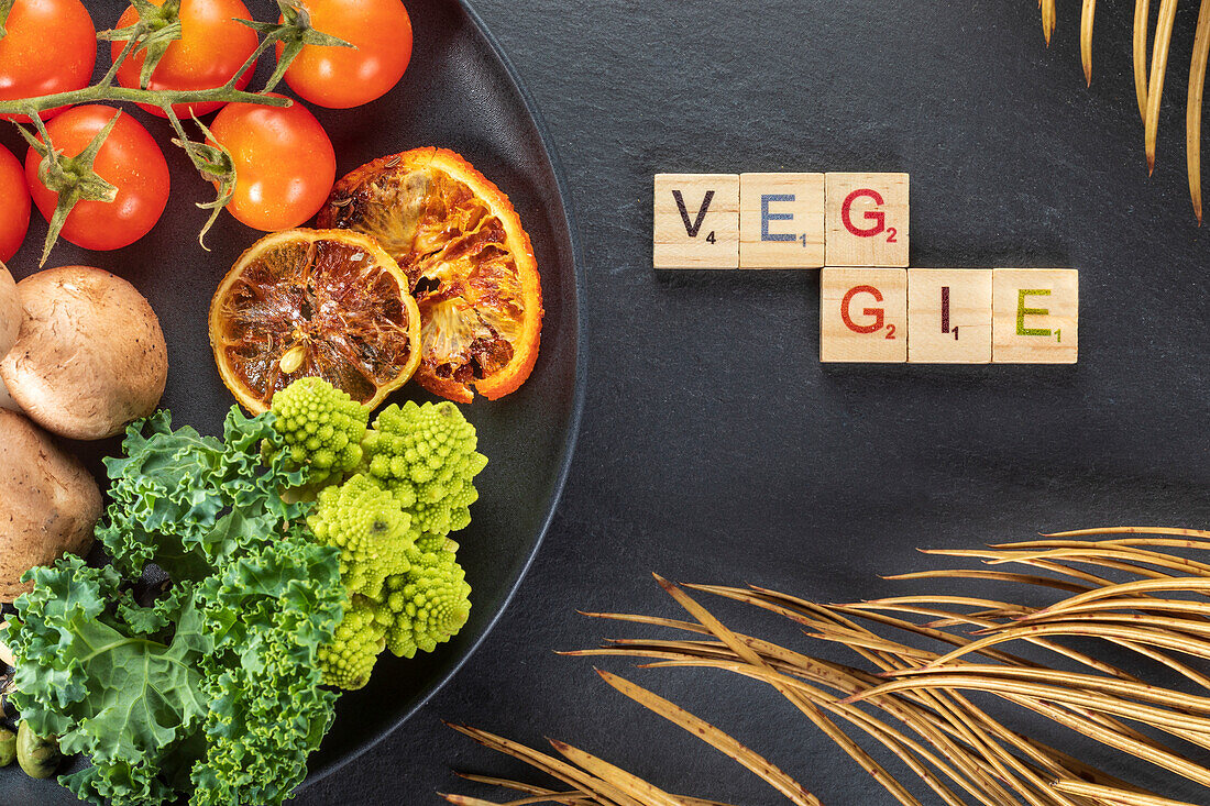 From above of decorative title near cooked potatoes with bunch of cherry tomatoes and sprouts on plate on gray background