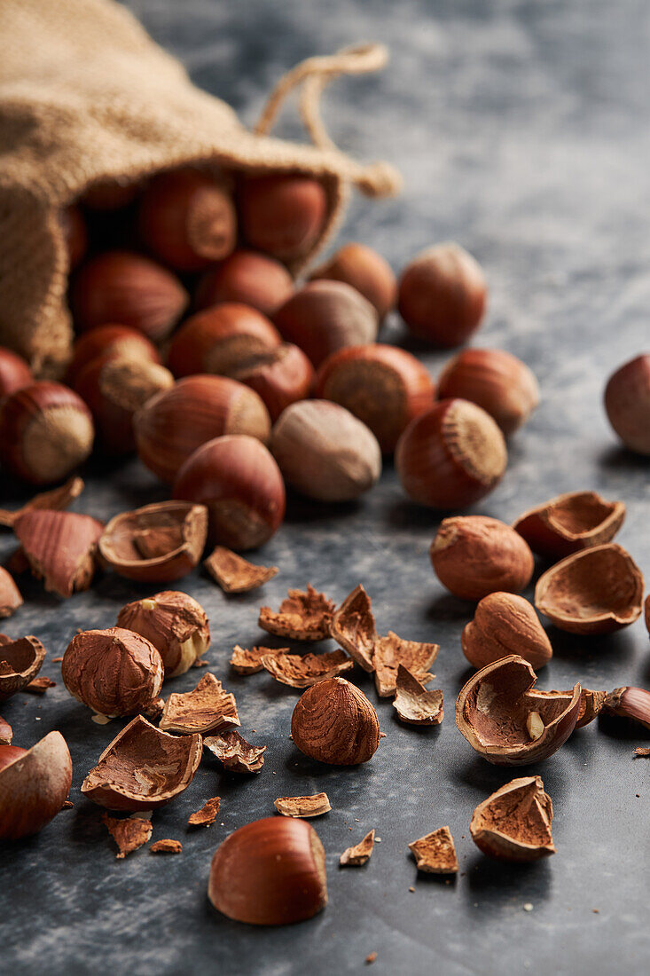 Bunch of ripe hazelnuts and shells scattered on marble table and burlap bag