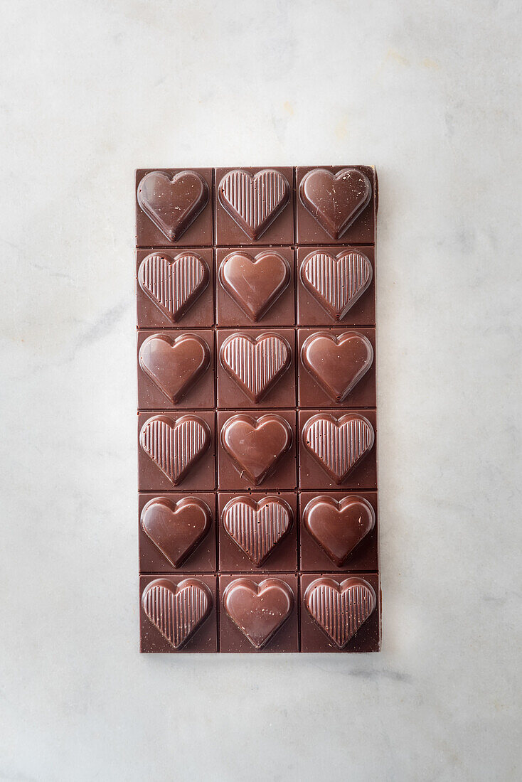 Draufsicht auf köstliche Schokoladenpralinen mit Nüssen in Herzform auf Marmortisch-Hintergrund