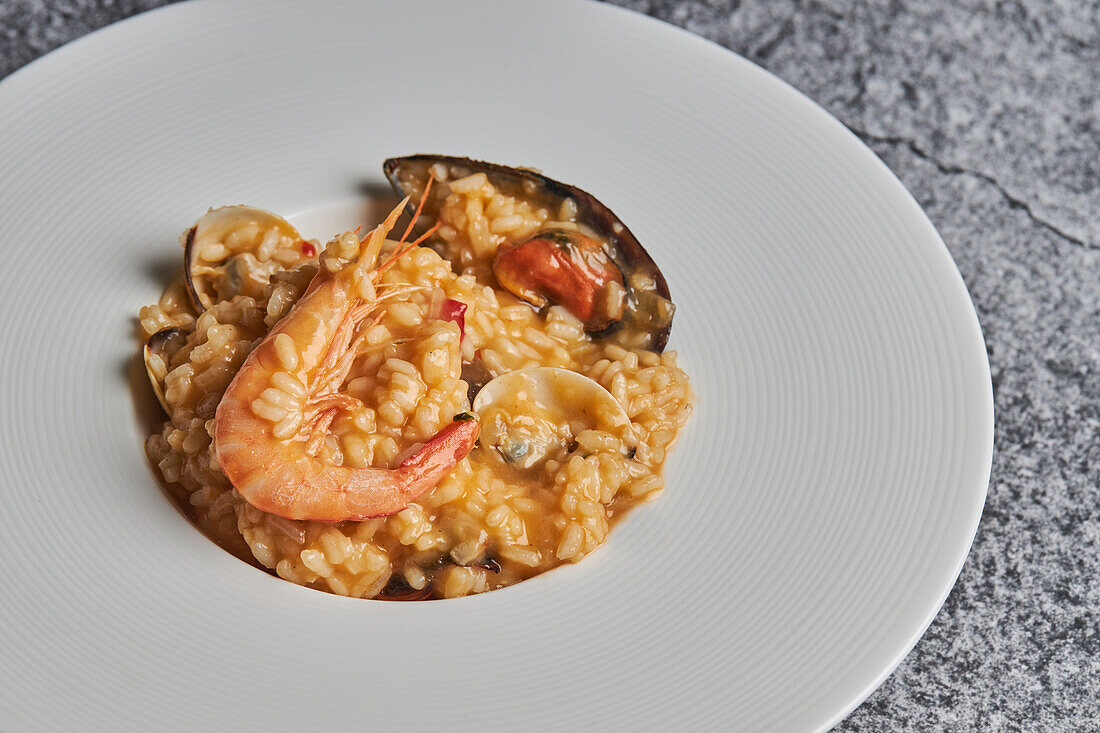 From above of appetizing rice with assorted seafood served on plate on table in restaurant