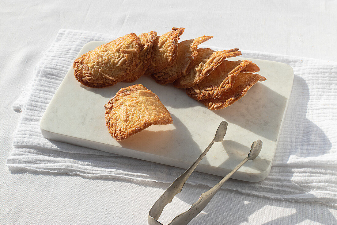 Top view of delicious Almond Tiles cookies placed on plate on tablecloth