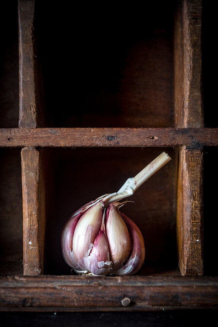 Whole head of fresh garlic placed on shabby wooden shelf in rustic kitchen