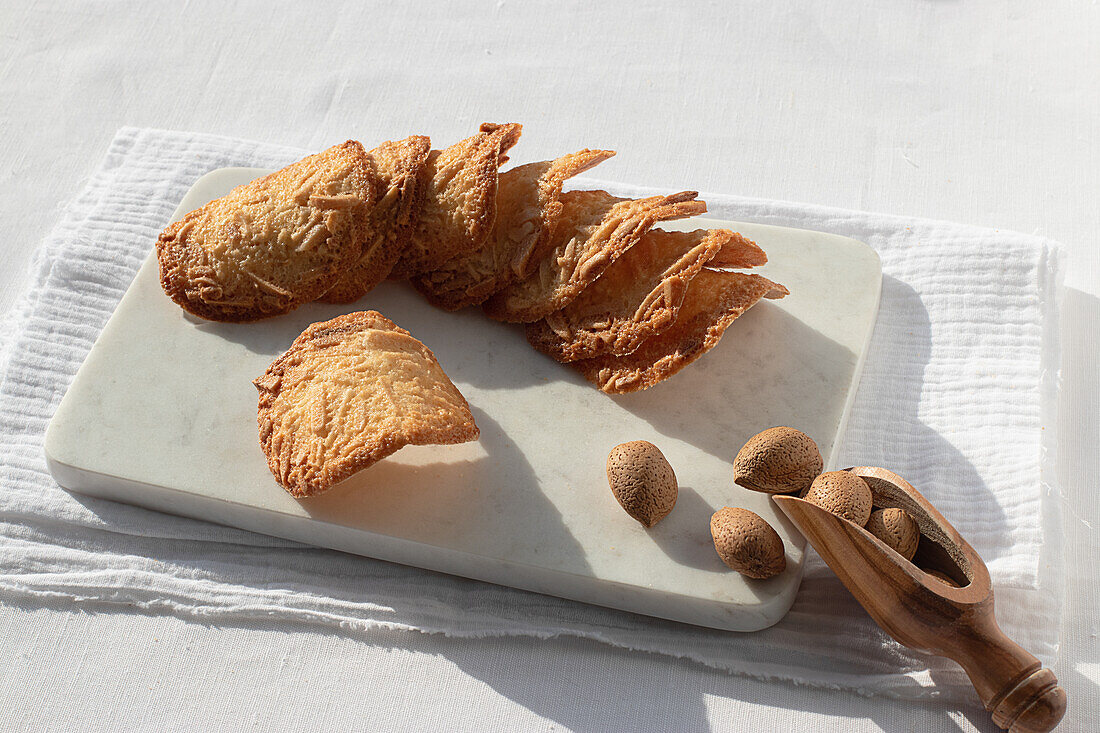 Top view of delicious Almond Tiles cookies placed on plate on tablecloth