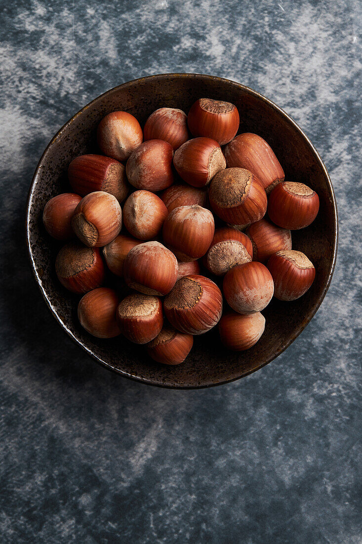 From above bunch of ripe hazelnuts in bowl on marble table