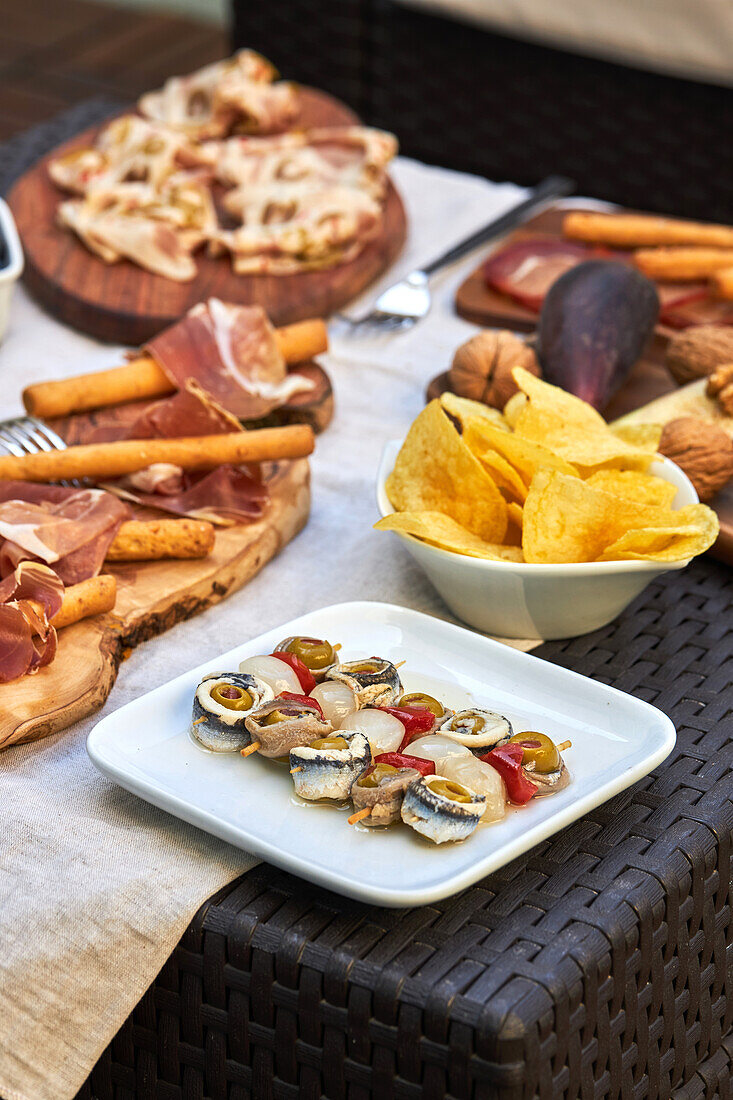Blick von oben auf köstliches, aufgespießtes, eingelegtes Gemüse mit Sardinen, Oliven, roter Paprika und Babyzwiebeln auf einem Tisch mit Snacksortiment