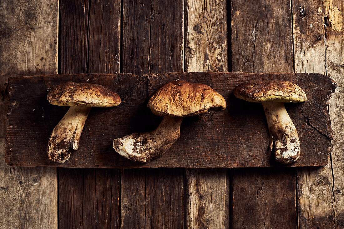 Draufsicht auf roh geschnittene Steinpilze (Boletus edulis) auf rustikalem Holzschneidebrett während des Kochvorgangs