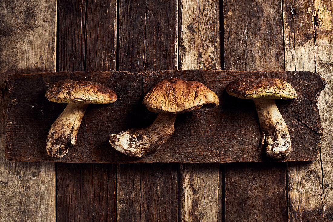 Top view of raw cut Boletus edulis mushrooms on rustic wooden chopping board during cooking process