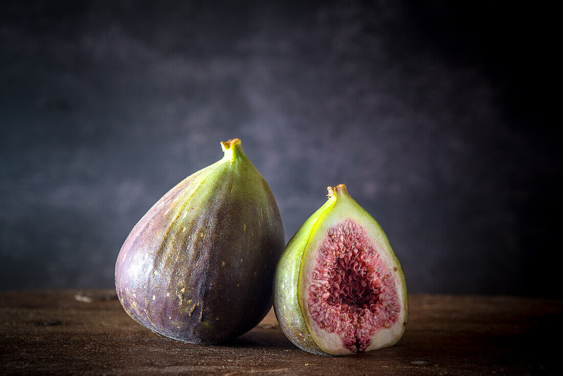 Ripe halved and whole figs placed on wooden rustic table