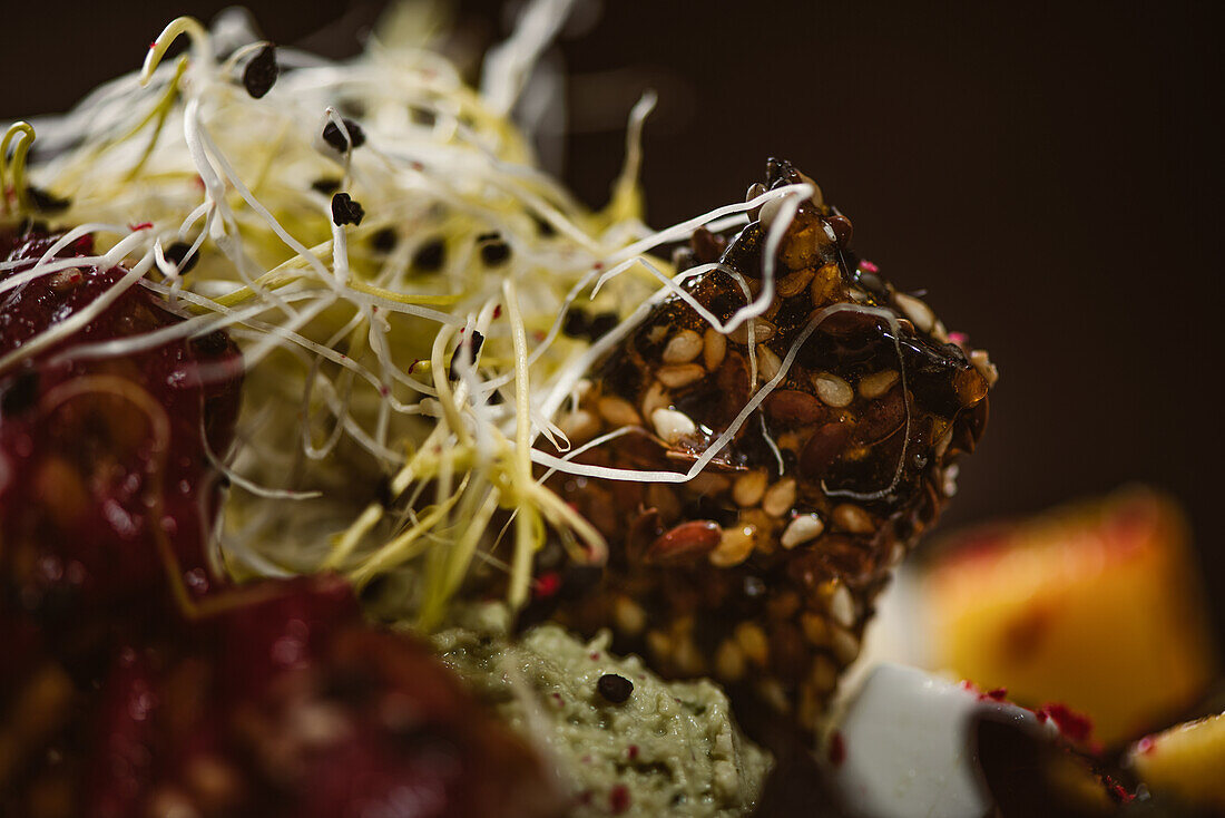 Nahaufnahme eines Tellers mit leckerem vegetarischem indonesischem Salat mit frischer Mango und Cashew-Käse-Scheiben neben Sojabohnen und Gewürzen mit Basilikum-Vinaigrette