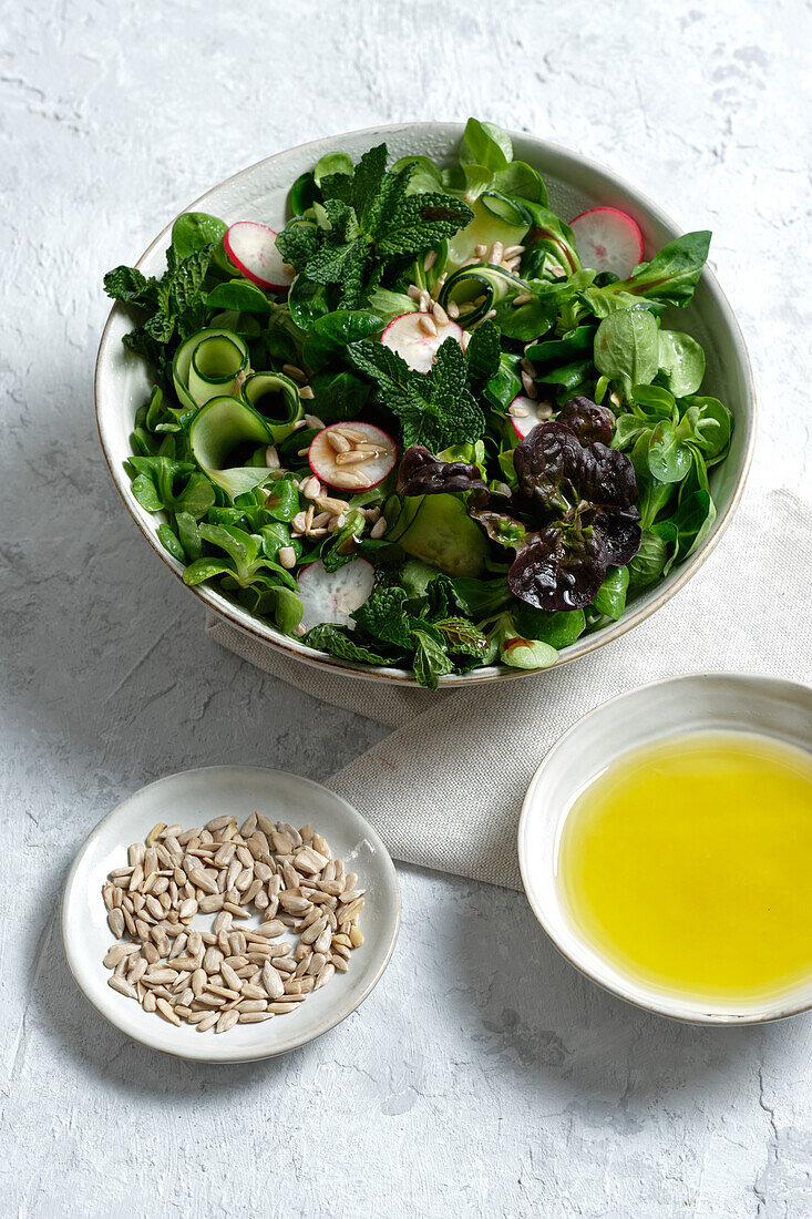 Top view of fresh healthy vegetable salad in bowl served on table with olive oil and sunflower seeds