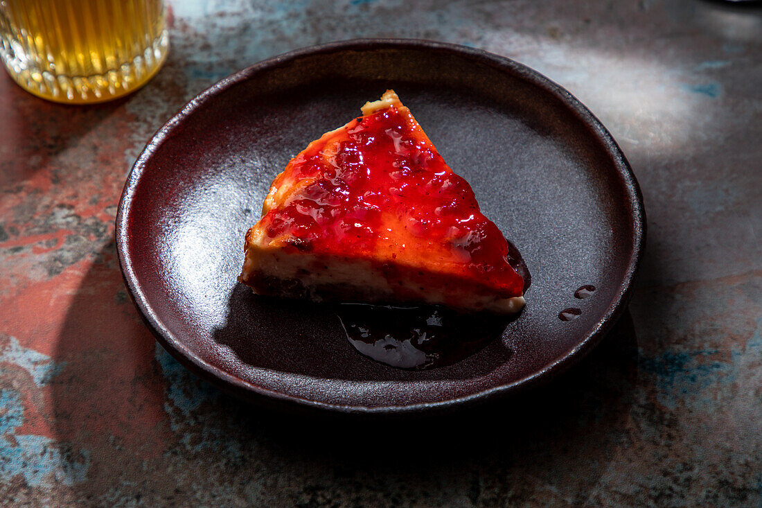 Von oben appetitlicher Kuchen mit Beerenmarmelade auf Keramikteller mit einem Glas Getränk mit Eis im Restaurant