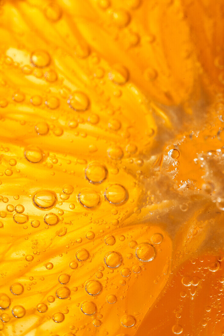 Close-up gin and tonic cocktail with slice of fresh orange bubbling in glass