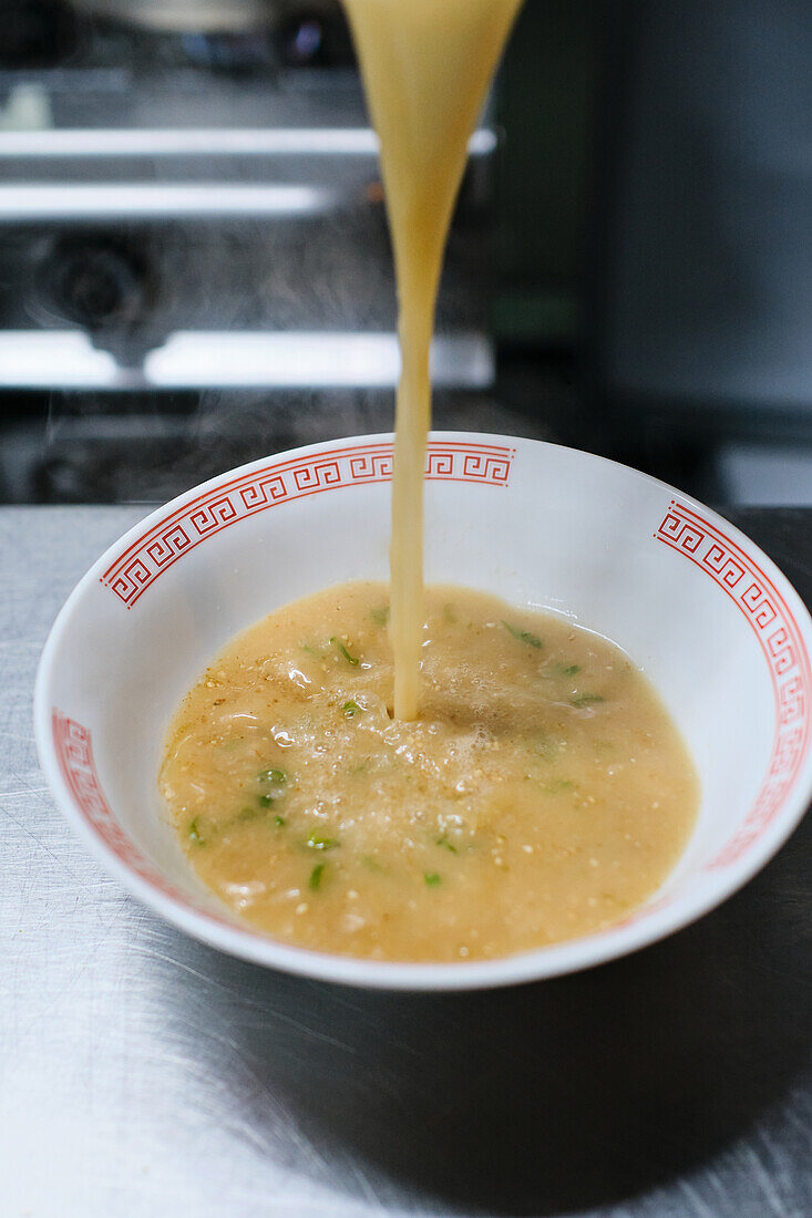 Stock photo of unrecognized chef in japanese restaurant serving noddles soup.