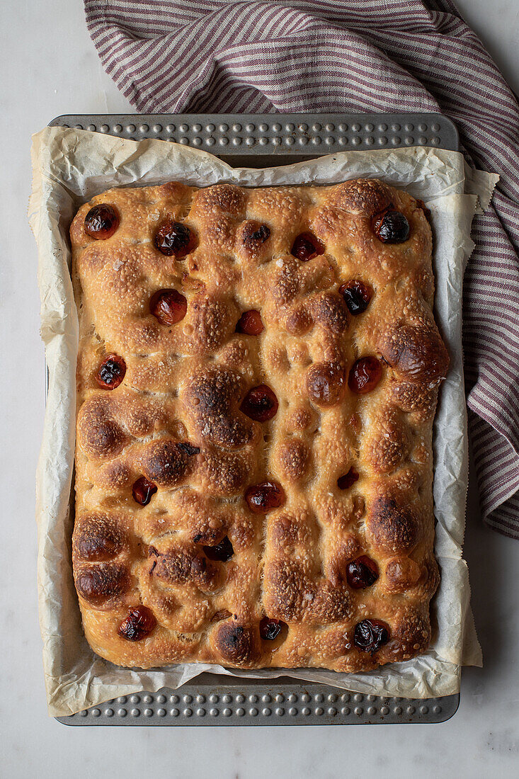 Top view of freshly baked traditional bread with tomatoes placed on baking paper