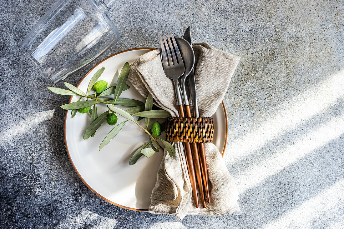 Rustic summer table setting with plate and cutlery decorated with Olive tree branches